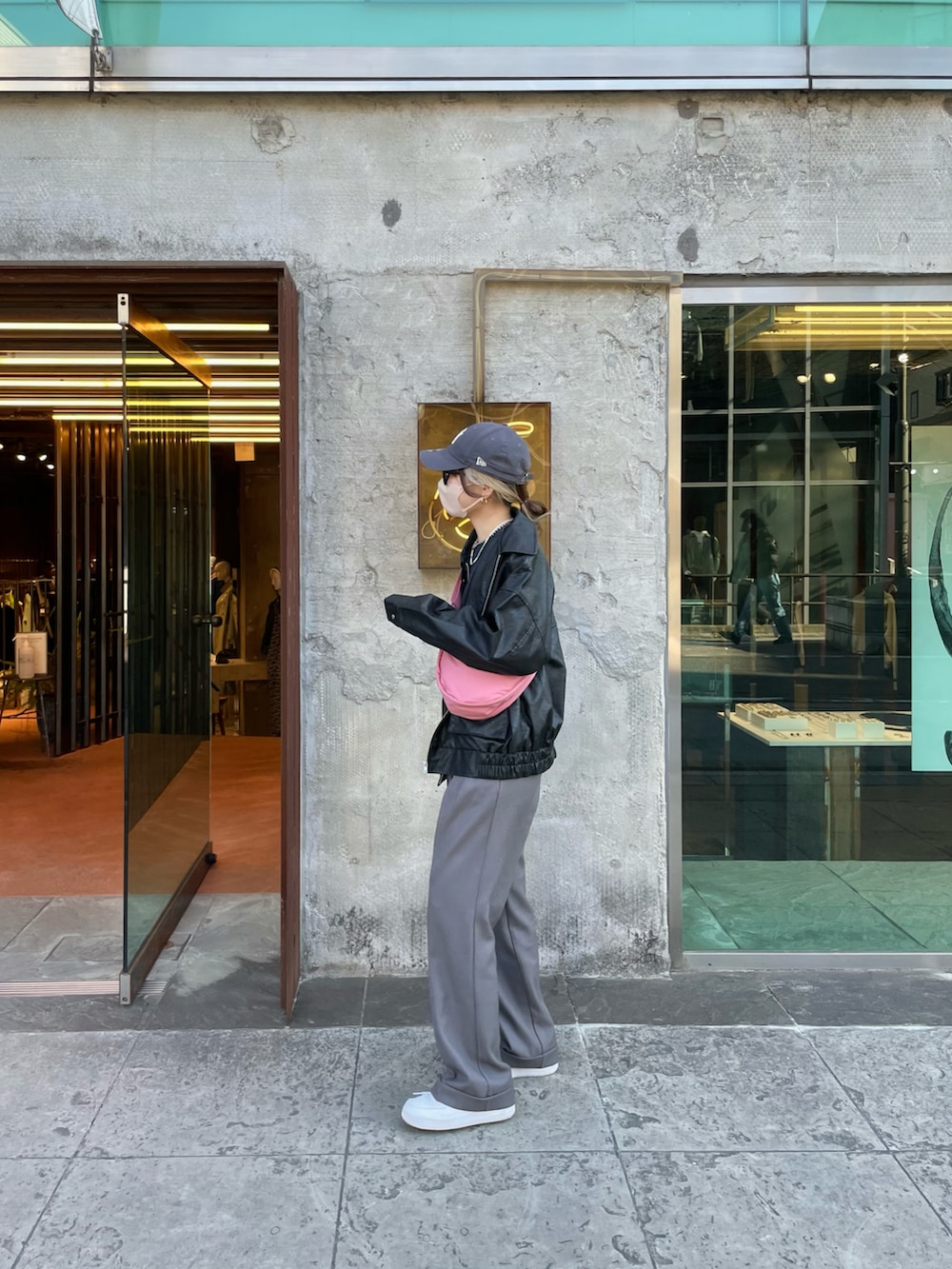 グレー系のパンツ、ピンク系のバッグ、ブラック系のブルゾンを着用したレディースの冬コーディネートの4枚目の写真