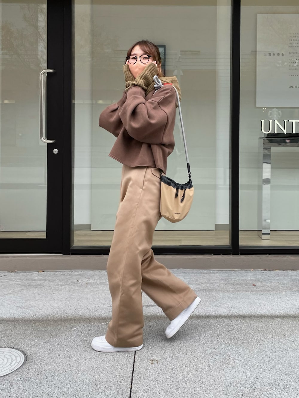 ブラウン系のスウェット、ベージュ系のバッグ、ベージュ系のパンツを着用したレディースの冬コーディネートの2枚目の写真