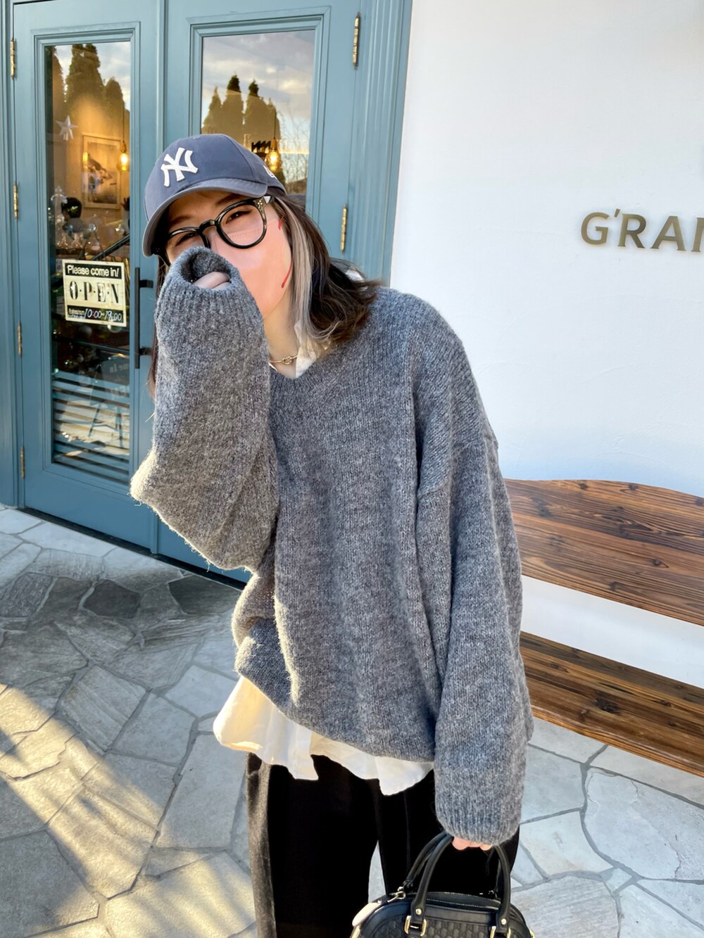 グレー系のニット/セーター、ブラック系のパンツ、ブラック系のバッグを着用したレディースの春コーディネートの2枚目の写真