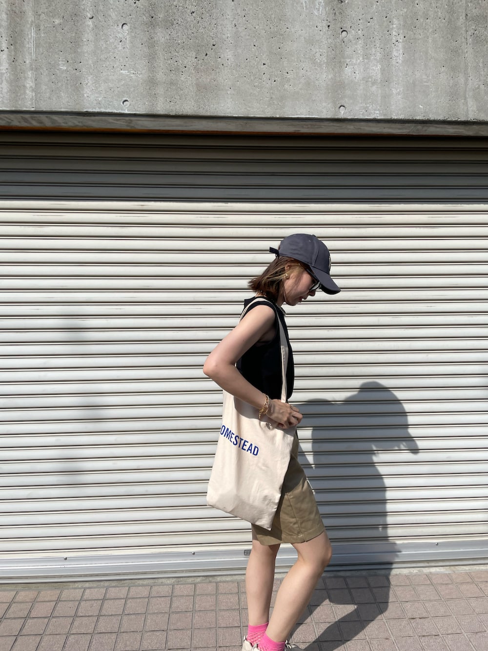 ホワイト系のトートバッグ、ブラック系のTシャツ/カットソー、ベージュ系のスニーカーを着用したレディースの夏コーディネートの3枚目の写真