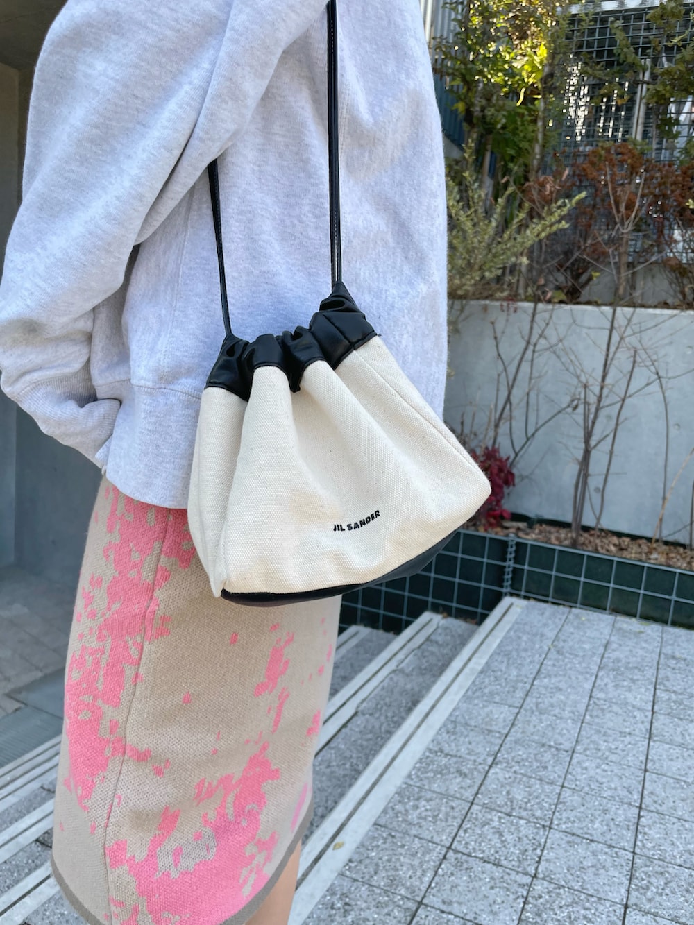 ピンク系のスカート、ブラック系のブーツ、グレー系のトップスを着用したレディースの春コーディネートの5枚目の写真
