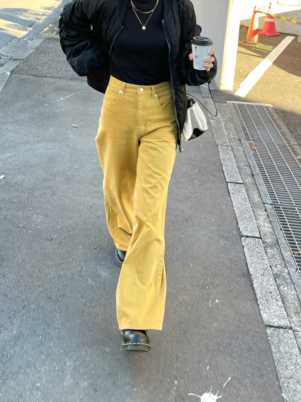 イエロー系のパンツ、ブラック系のMA-1、ブラック系のトップスを着用したレディースの春コーディネートの4枚目の写真
