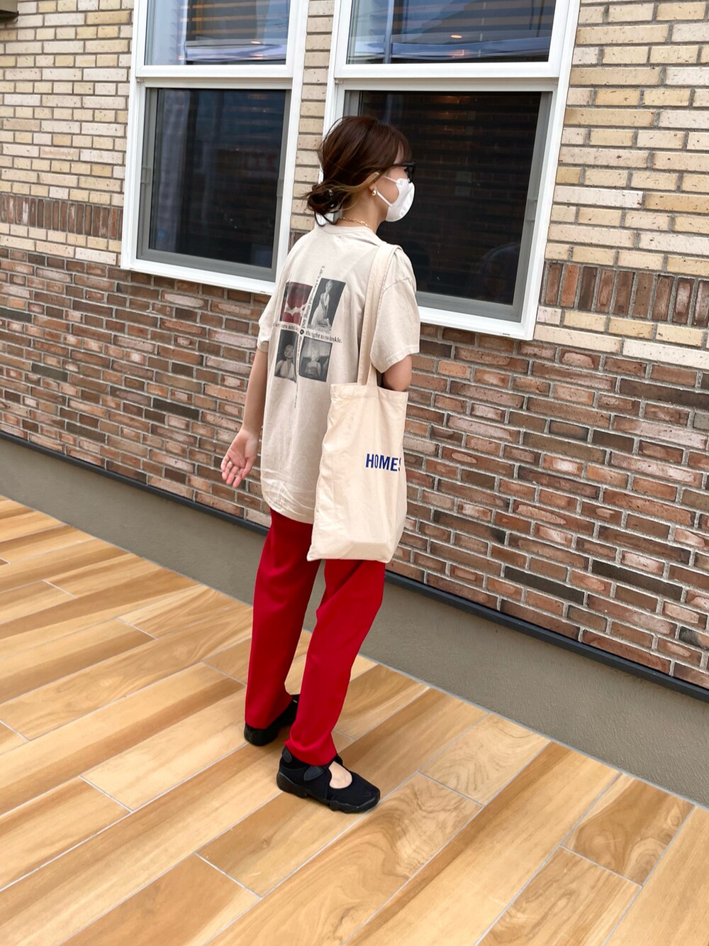 レッド系のスラックス、ブラック系のサンダル、ホワイト系のトートバッグを着用したレディースの夏コーディネートの2枚目の写真