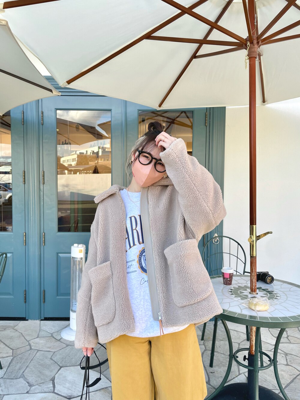 イエロー系のパンツ、ベージュ系のその他アウター、ホワイト系のショルダーバッグを着用したレディースの冬コーディネートの2枚目の写真