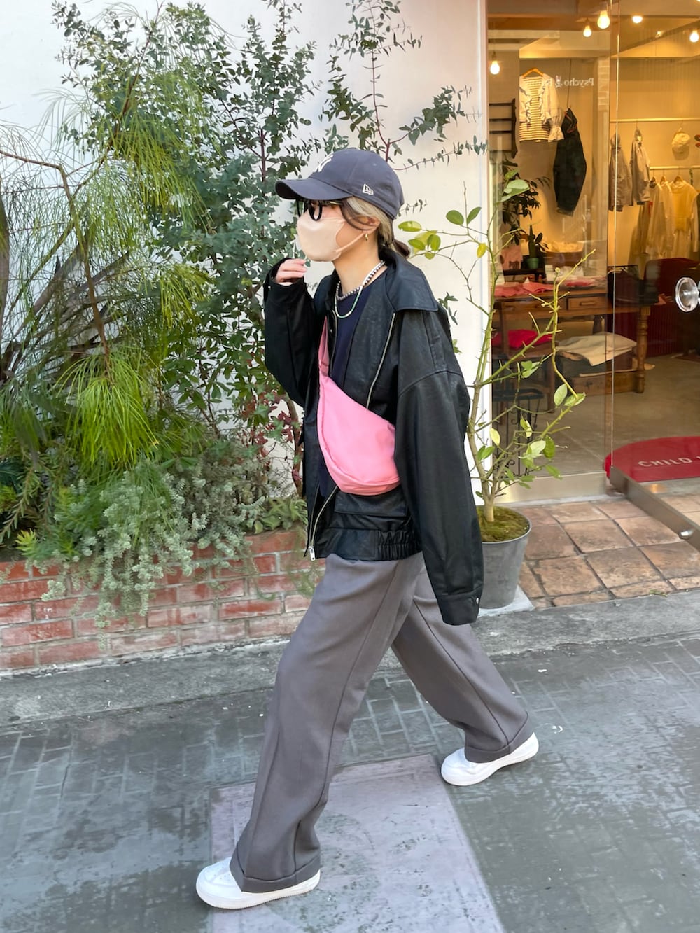 グレー系のパンツ、ピンク系のバッグ、ブラック系のブルゾンを着用したレディースの冬コーディネートの2枚目の写真