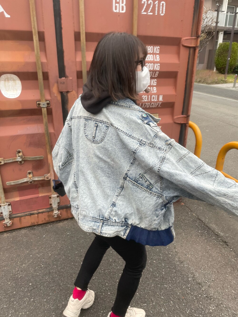 ブルー系のデニムジャケット、ブラック系のパーカー、ブルー系のバッグを着用したレディースの春コーディネートの5枚目の写真