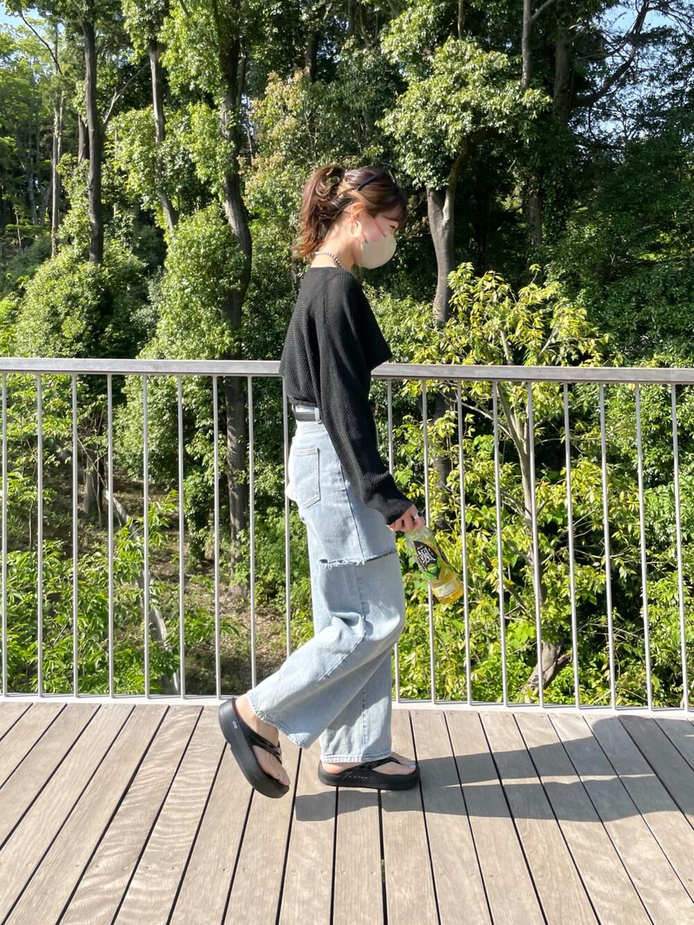 ブルー系のデニムパンツ、ブラック系のトップス、ブラック系のサンダルを着用したレディースの春コーディネートの5枚目の写真