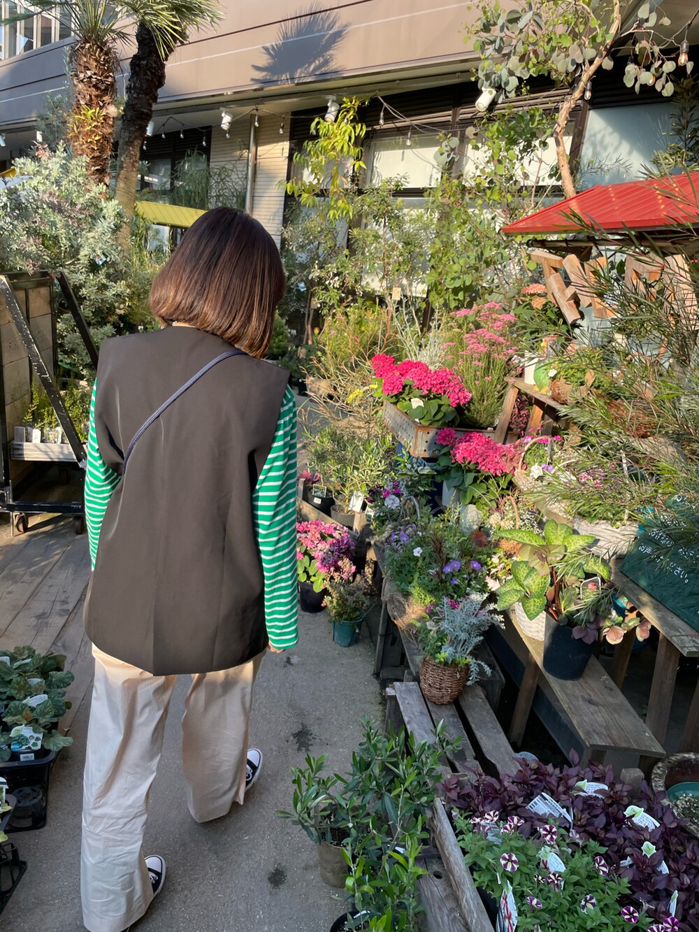 グリーン系のTシャツ/カットソー、ブラック系のベスト、ベージュ系のパンツを着用したレディースの春コーディネートの3枚目の写真