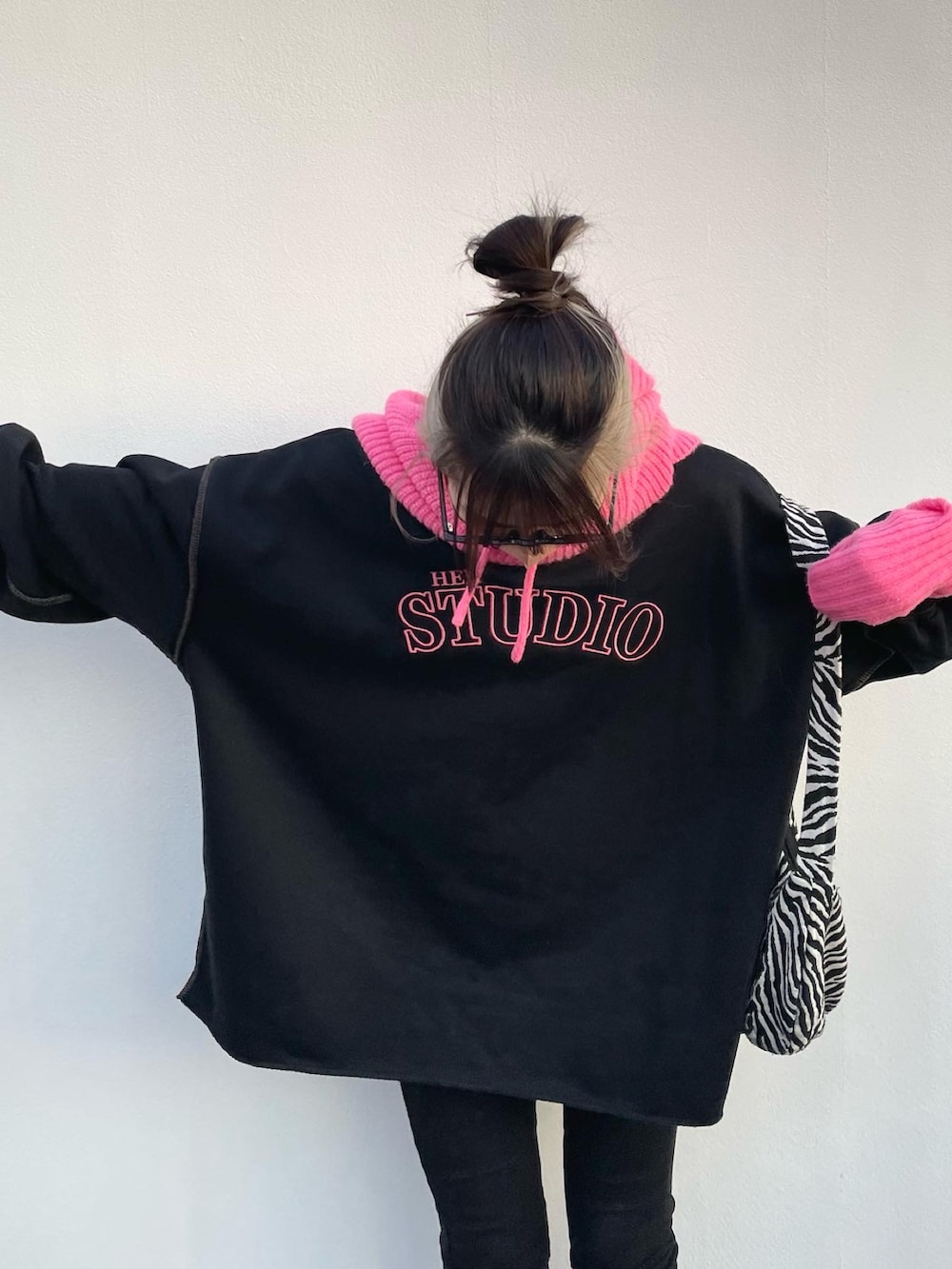 ブラック系のスウェット、ブラック系のブーツ、ピンク系のアームカバーを着用したレディースの冬コーディネートの4枚目の写真