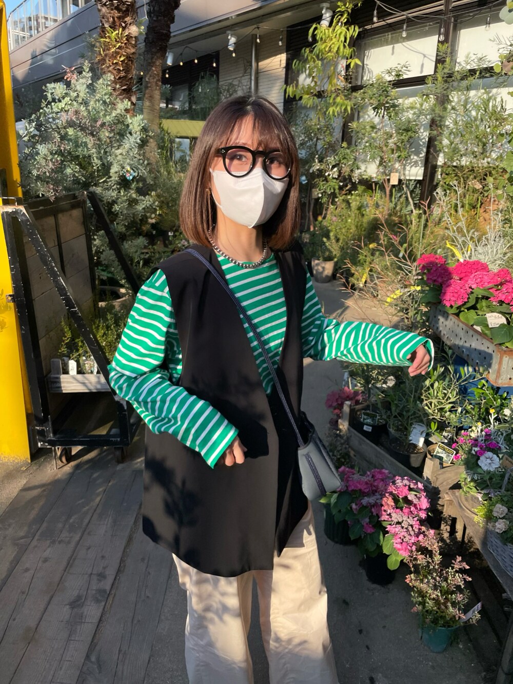 グリーン系のTシャツ/カットソー、ブラック系のベスト、ベージュ系のパンツを着用したレディースの春コーディネートの2枚目の写真