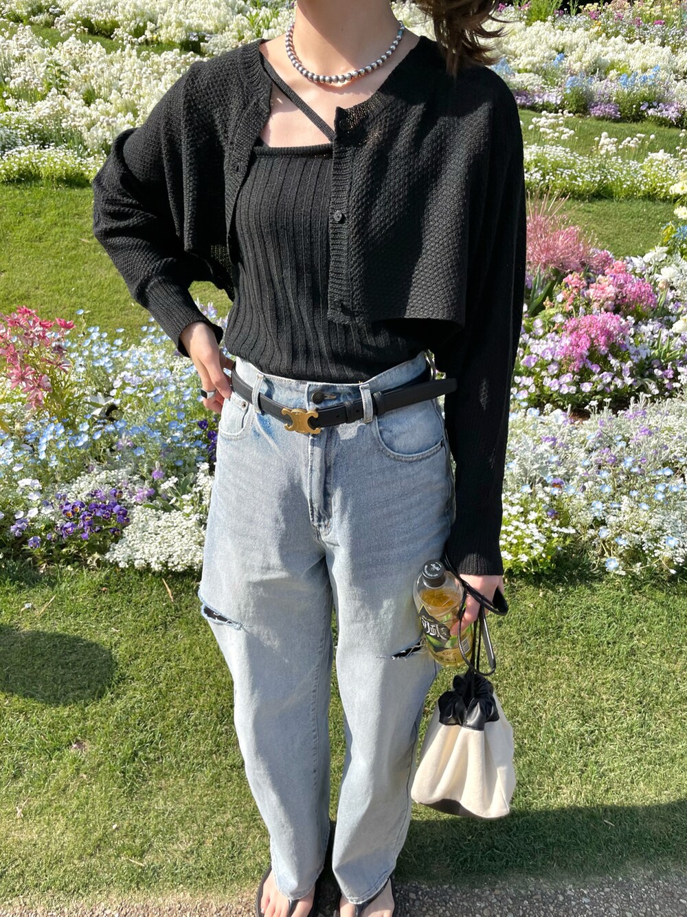 ブルー系のデニムパンツ、ブラック系のトップス、ブラック系のサンダルを着用したレディースの春コーディネートの2枚目の写真