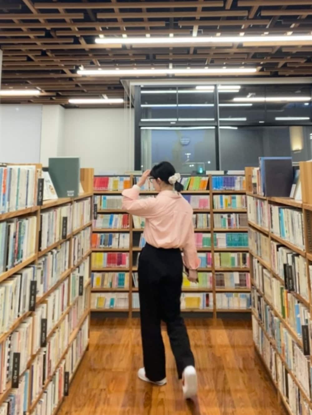 ブラック系のスラックス、ピンク系のシャツ/ブラウス、ホワイト系のスニーカーを着用したレディースの春コーディネートの2枚目の写真