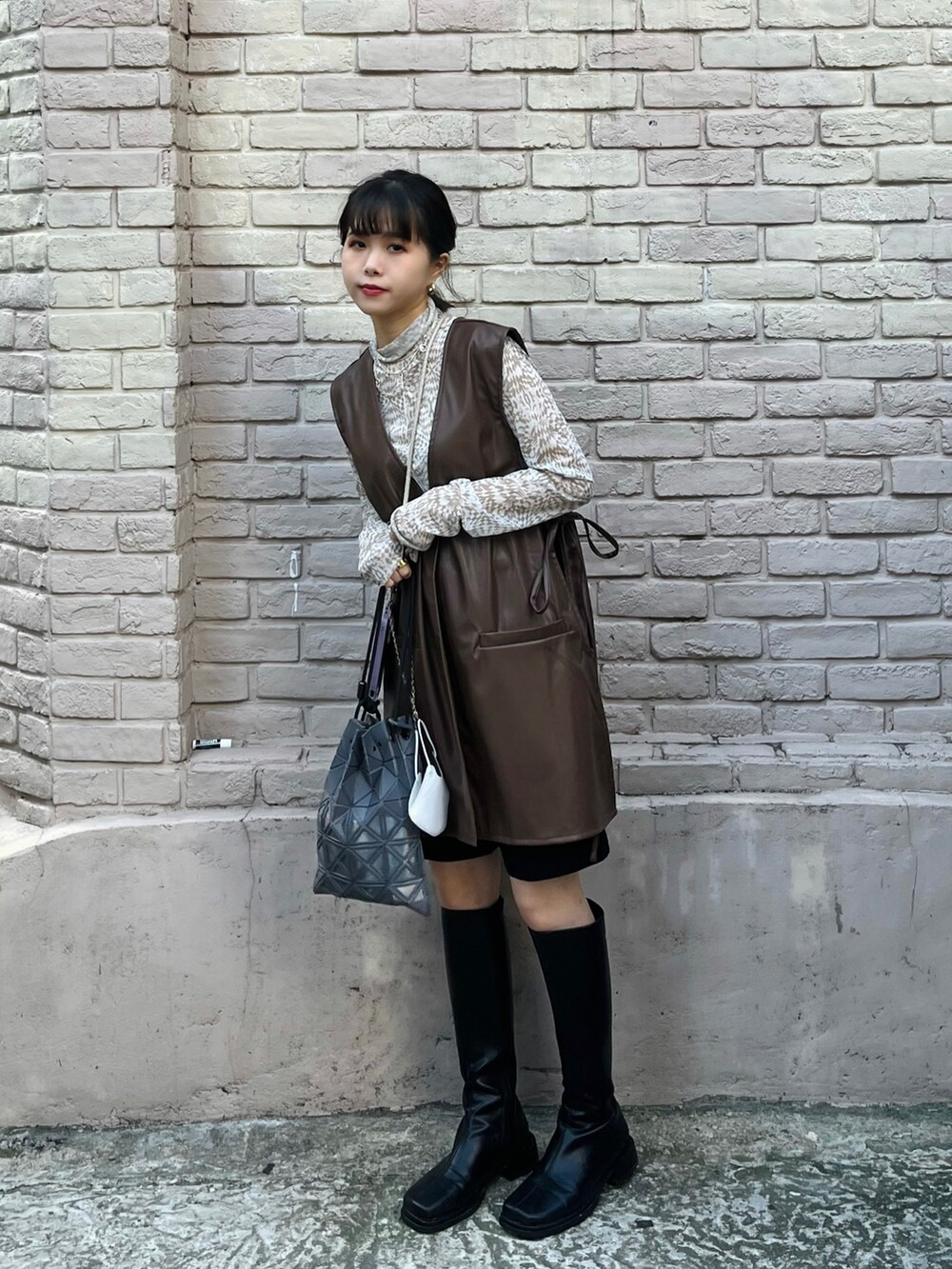 ブラウン系のベスト、ベージュ系のトップス、グレー系のバッグを着用したレディースの秋コーディネートの3枚目の写真