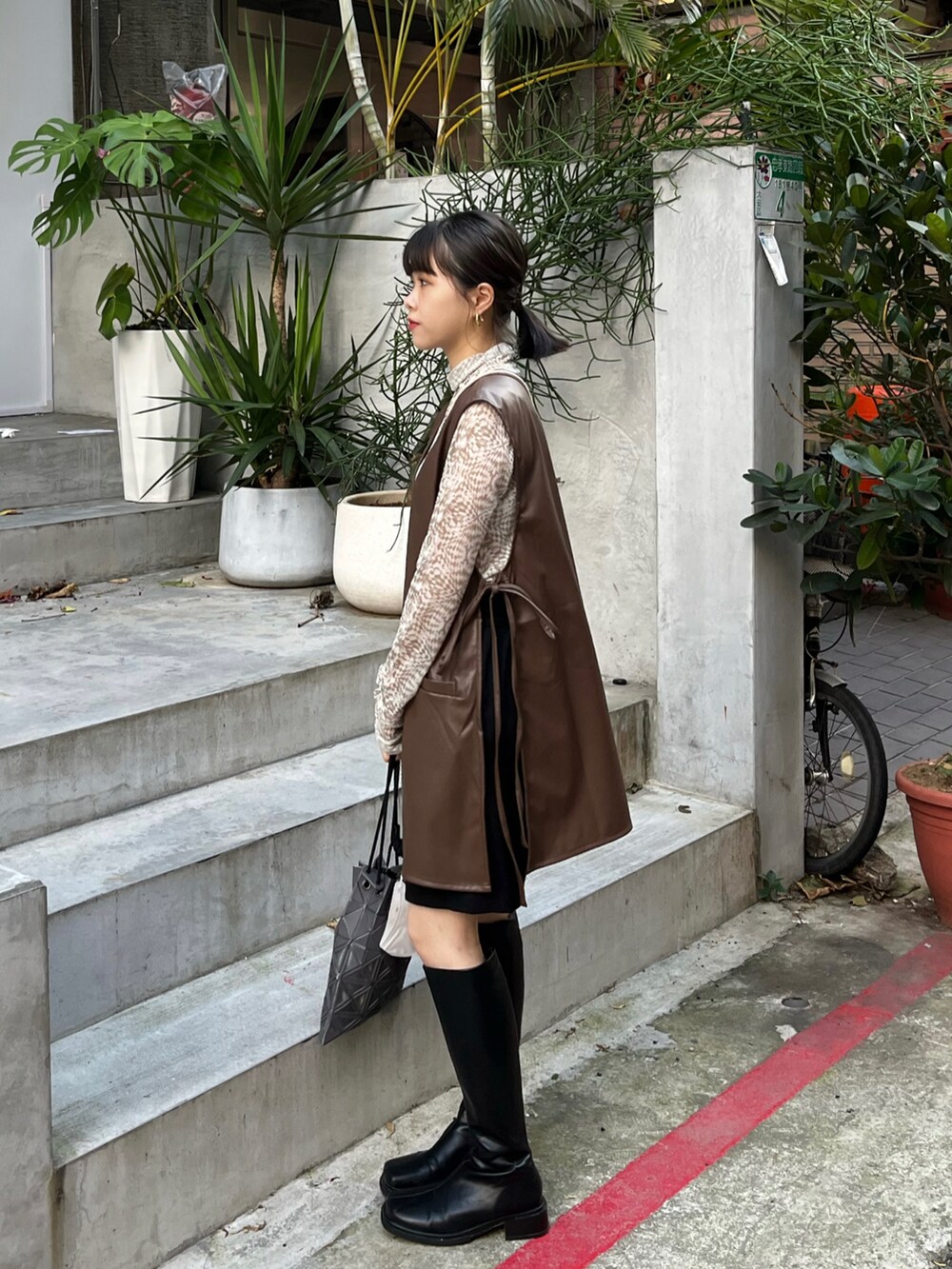 ブラウン系のベスト、ベージュ系のトップス、グレー系のバッグを着用したレディースの秋コーディネートの2枚目の写真