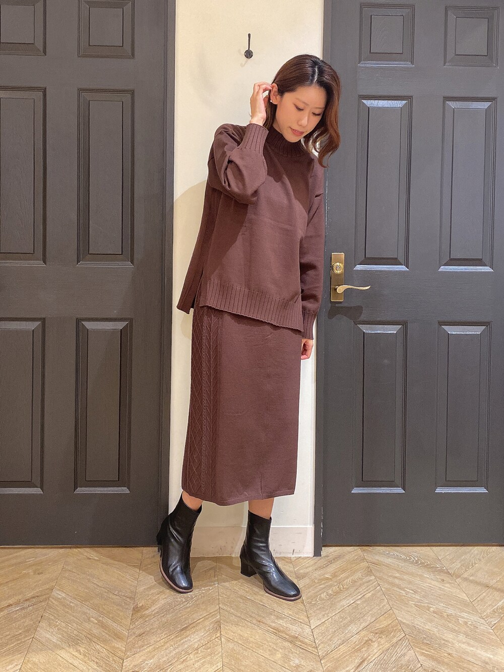 ブラウン系のスカート、ブラウン系のニット/セーター、ブラック系のショルダーバッグを着用したレディースの秋コーディネートの3枚目の写真