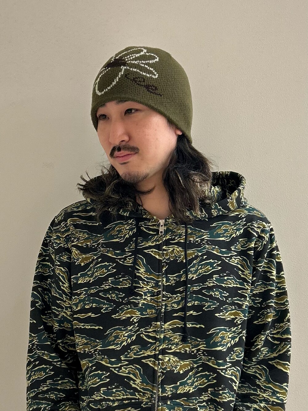 グリーン系のニットキャップ/ビーニーを着用したメンズの冬コーディネートの2枚目の写真