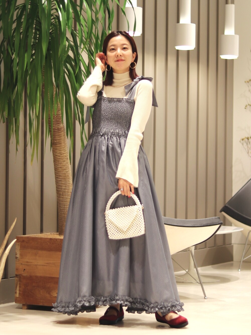 ホワイト系のステンカラーコート、ホワイト系のメッセンジャーバッグ、レッド系のシューズを着用したレディースの秋コーディネートの2枚目の写真