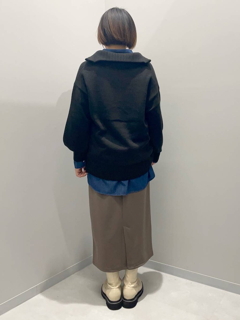 ブラック系のニット/セーター、ブルー系のシャツ/ブラウス、ブラウン系のスカートを着用したレディースの秋コーディネートの4枚目の写真