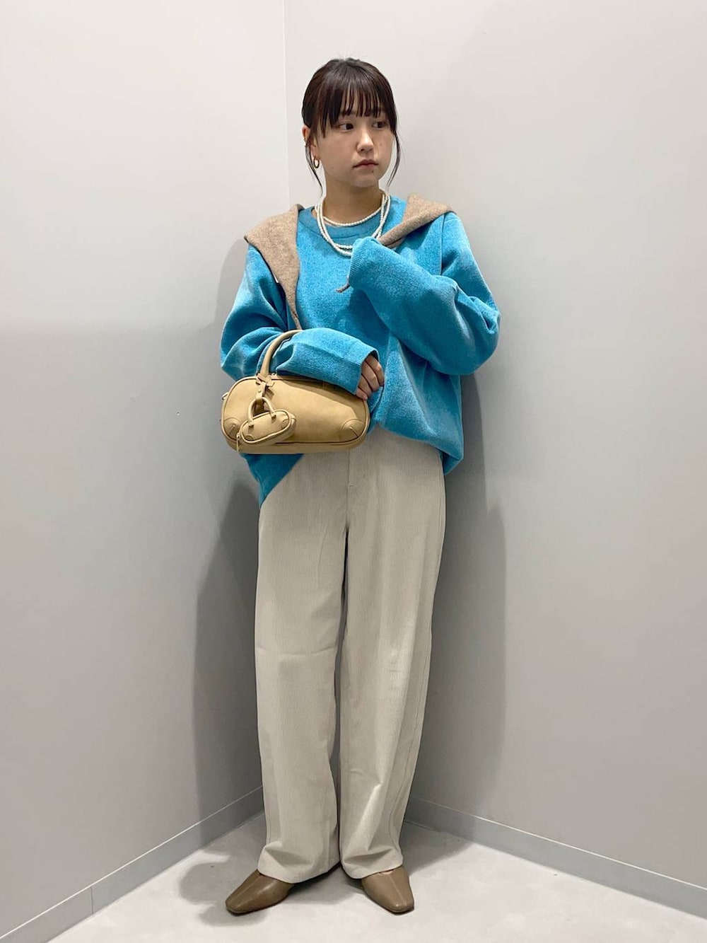 グレー系のその他パンツ、ブルー系のニット/セーター、ブラウン系のハンドバッグを着用したレディースの秋コーディネートの2枚目の写真