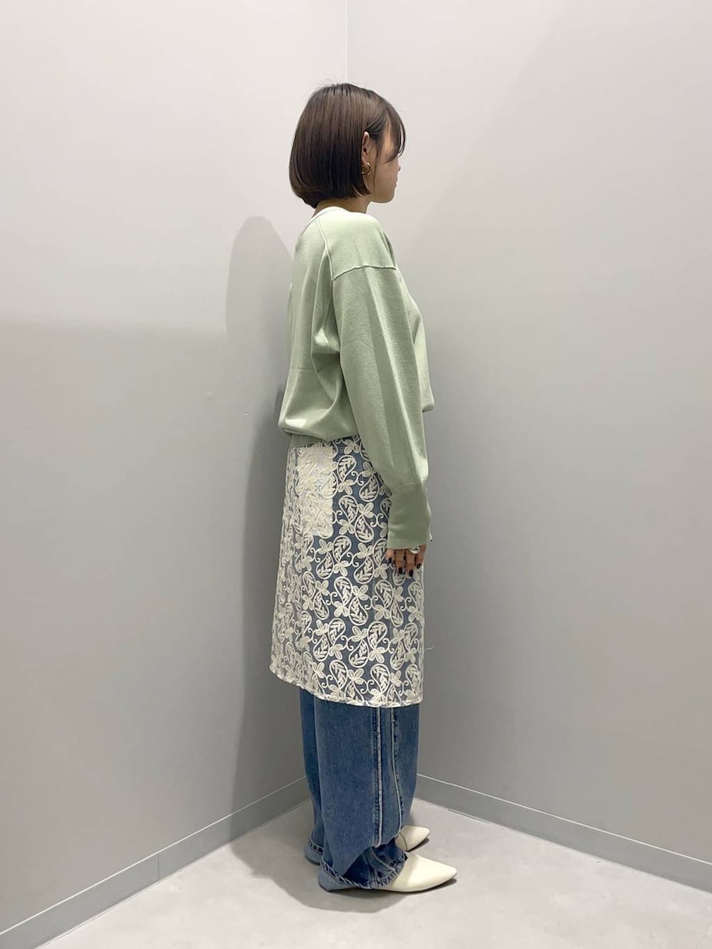 ホワイト系のデニムパンツ、グリーン系のニット/セーター、ホワイト系のその他小物を着用したレディースの春コーディネートの2枚目の写真