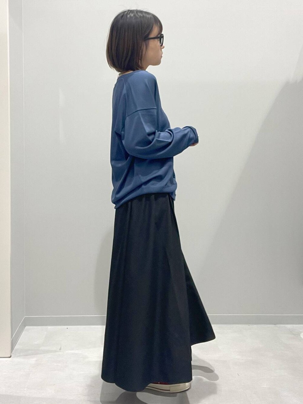ブラック系のスカート、ブルー系のカーディガン/ボレロ、グレー系のネックレスを着用したレディースの春コーディネートの2枚目の写真