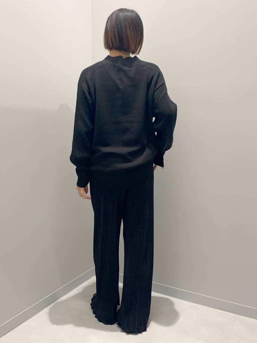 ブラック系のニット/セーター、ブラック系のその他パンツ、イエロー系のネックレスを着用したレディースの秋コーディネートの2枚目の写真