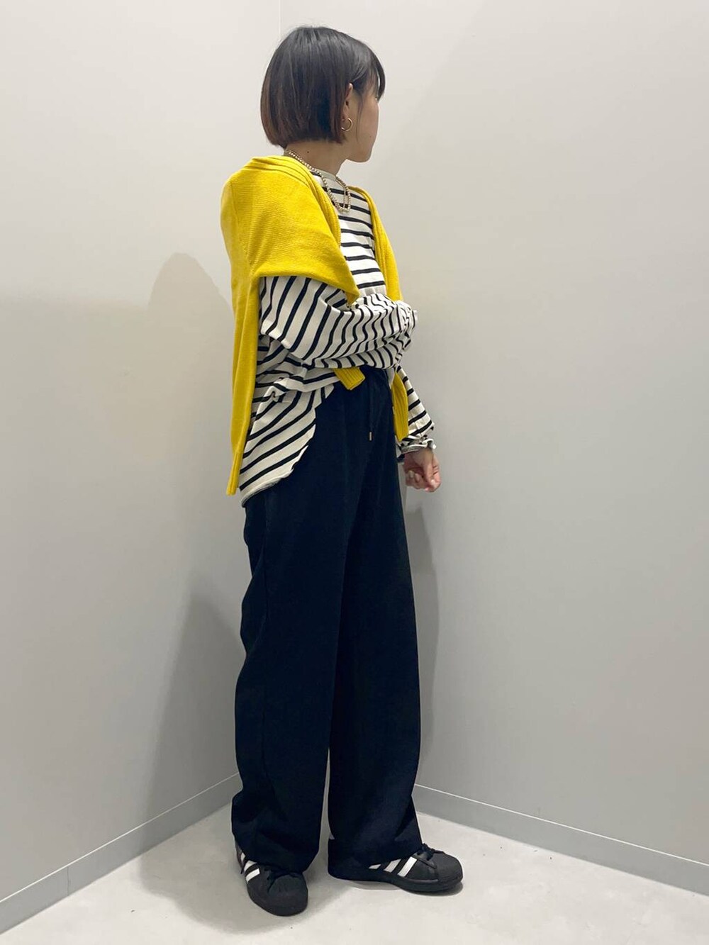 イエロー系のニット/セーター、グレー系のTシャツ/カットソー、ブラック系のその他パンツを着用したレディースの秋コーディネートの3枚目の写真