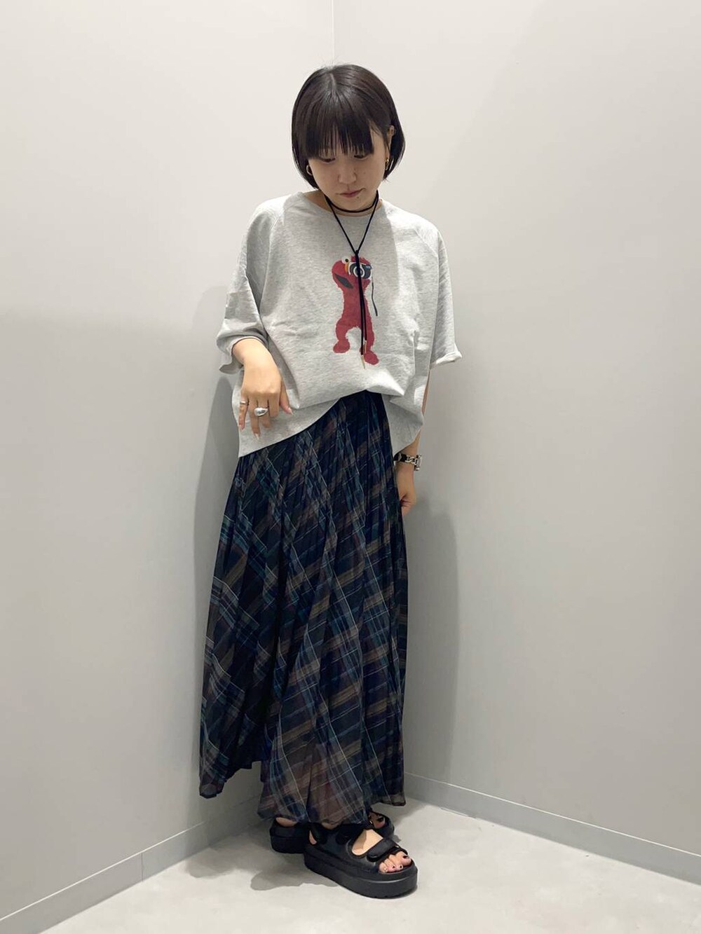 ブラック系のスカート、ゴールド系のチョーカーを着用したレディースの夏コーディネートの2枚目の写真