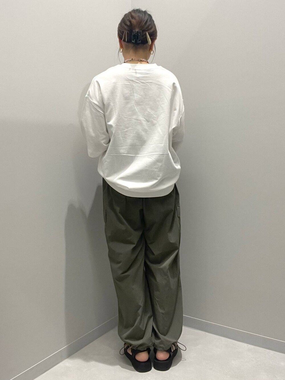 グリーン系のカーゴパンツ、ホワイト系のTシャツ/カットソー、オレンジ系のネックレスを着用したレディースの春コーディネートの3枚目の写真