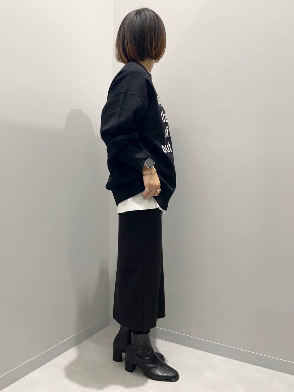 ブラック系のニット/セーター、ホワイト系のTシャツ/カットソー、ブラック系のスカートを着用したレディースの秋コーディネートの3枚目の写真