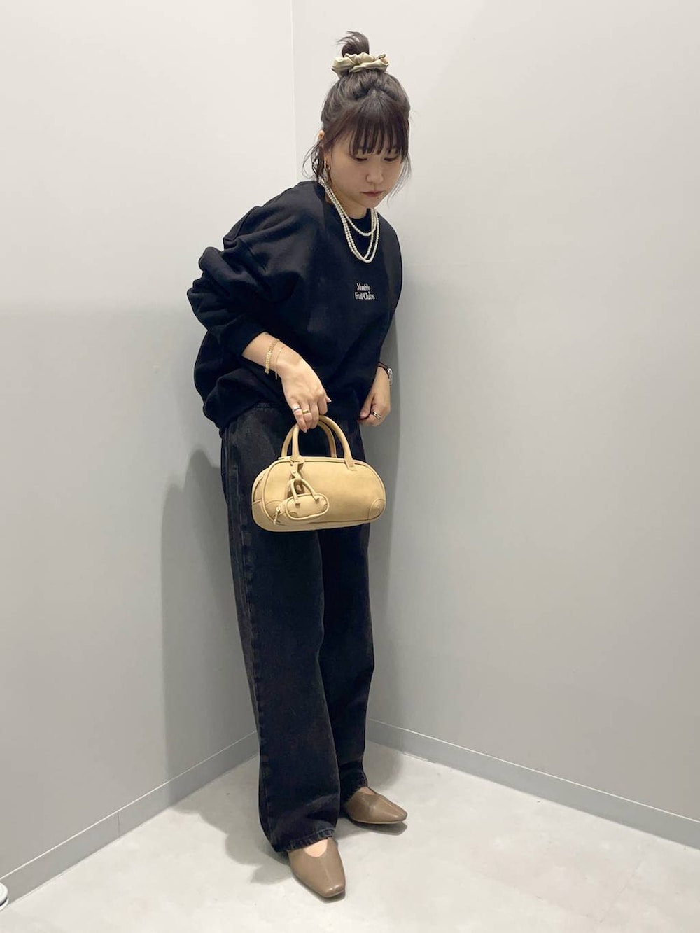 ブラック系のデニムパンツ、ブラウン系のハンドバッグ、ブラック系のスウェットを着用したレディースの秋コーディネートの2枚目の写真