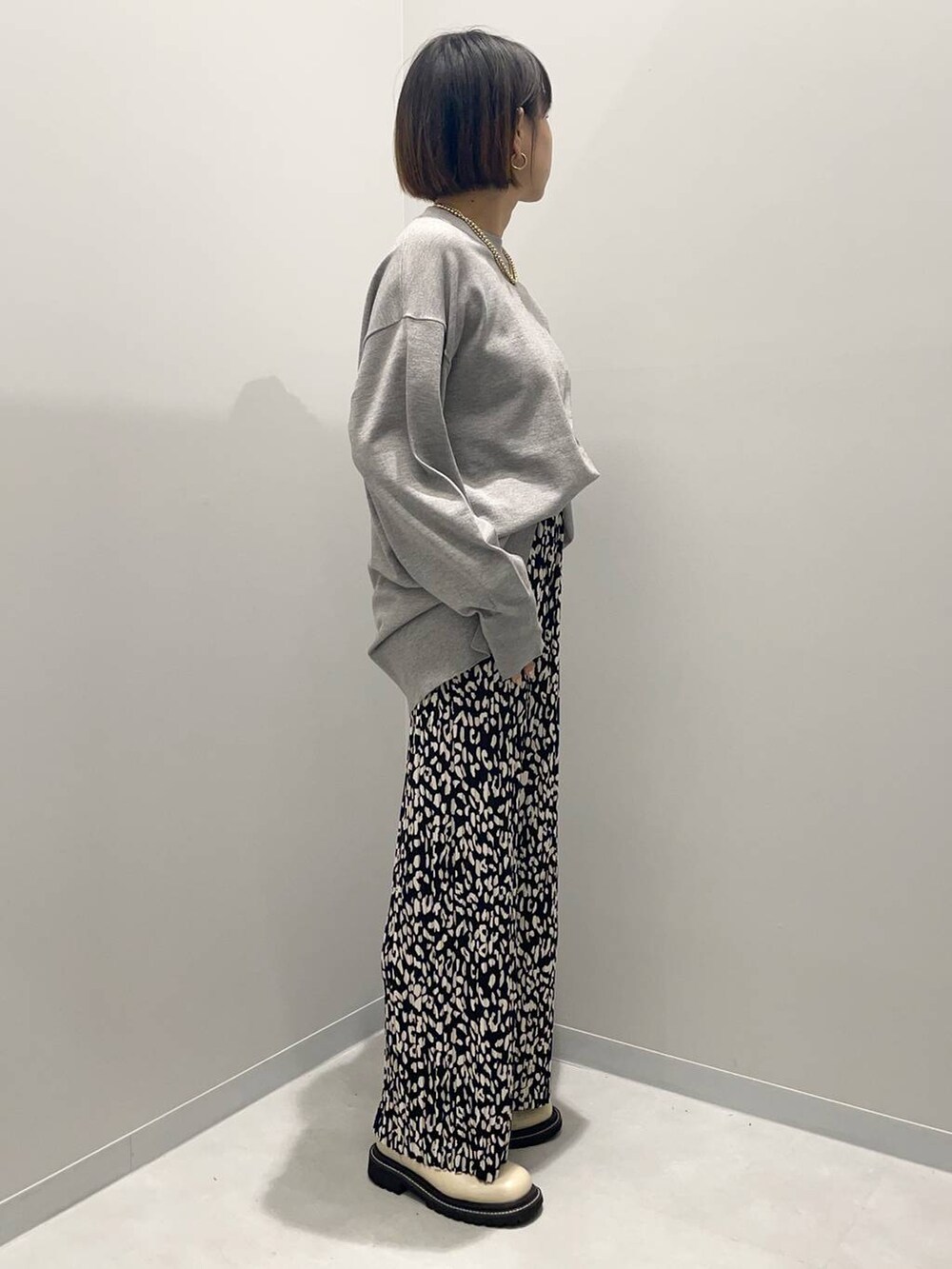 グレー系のニット/セーター、グレー系のその他パンツ、イエロー系のネックレスを着用したレディースの秋コーディネートの3枚目の写真