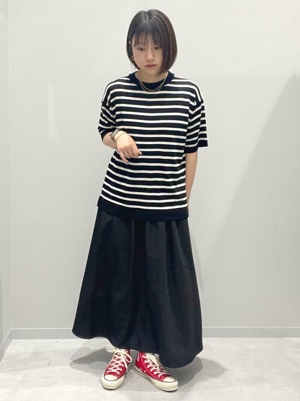 ブラック系のスカート、グレー系のニット/セーター、ホワイト系のネックレスを着用したレディースの春コーディネートの2枚目の写真