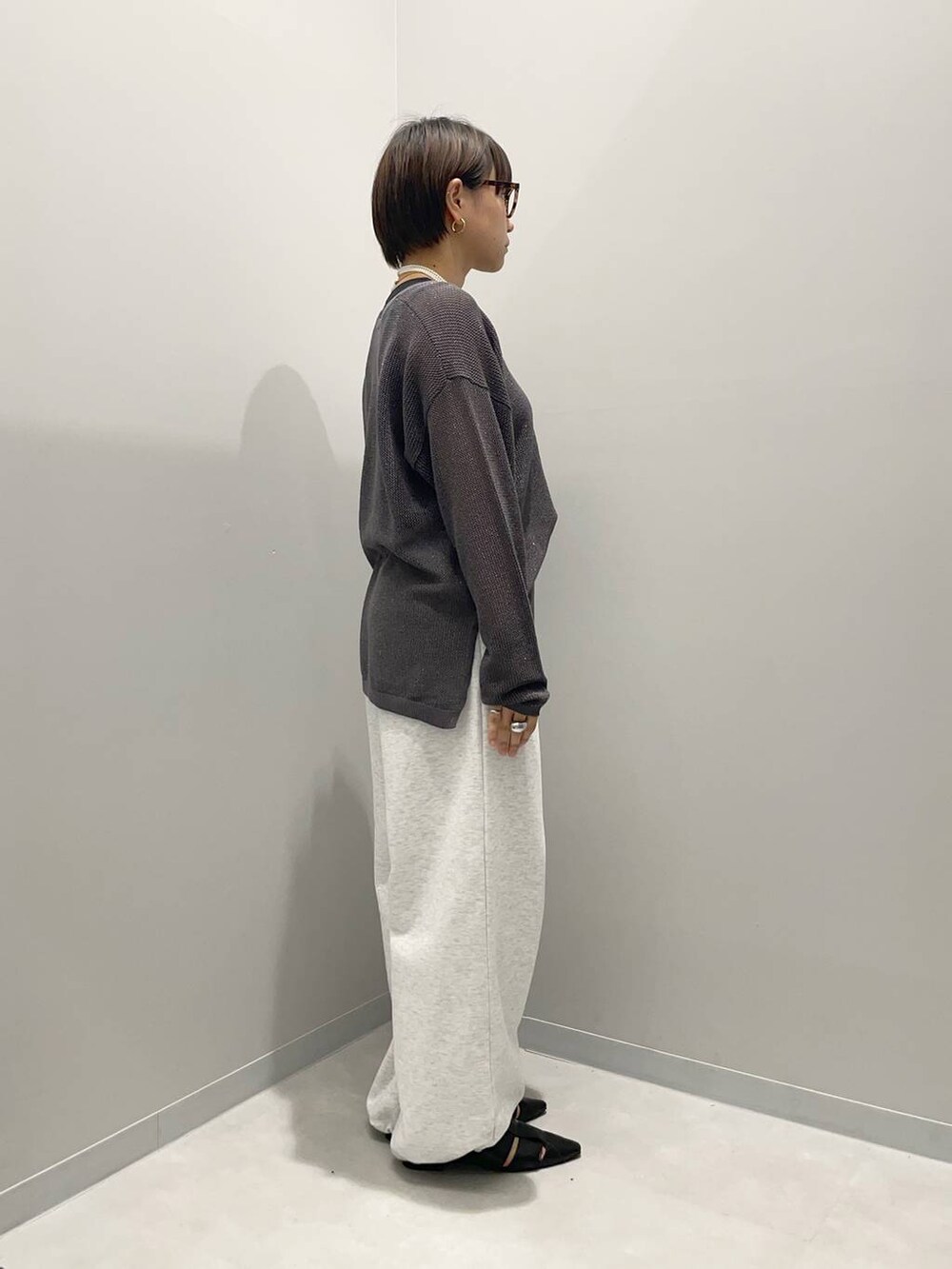 グレー系のニット/セーター、グレー系のスウェットパンツ、ブラック系のパンプスを着用したレディースの春コーディネートの2枚目の写真