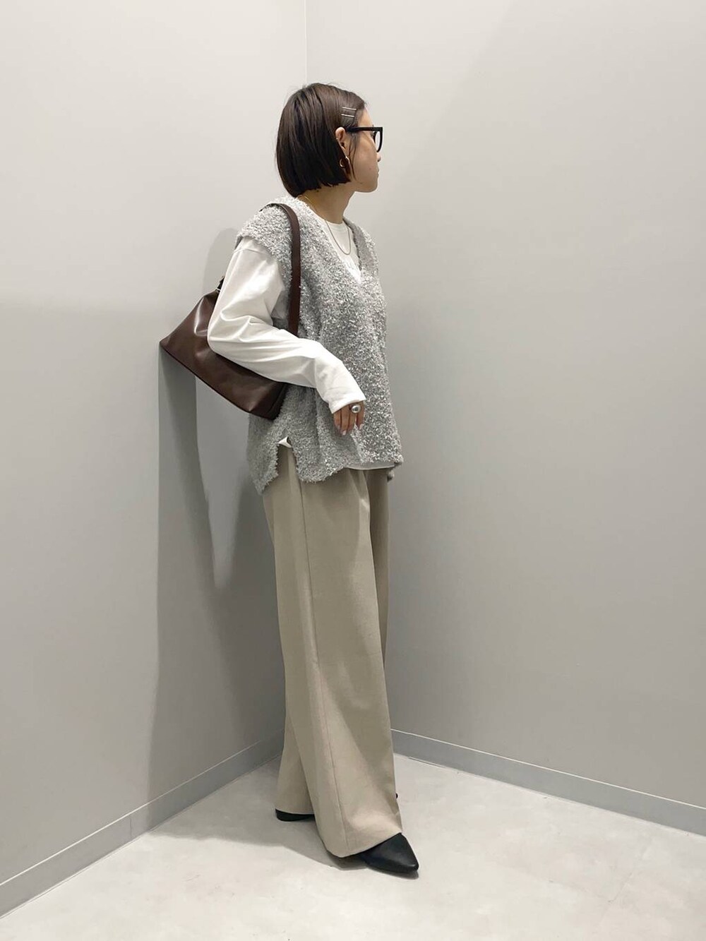 ブラウン系のショルダーバッグ、ベージュ系のその他パンツ、グレー系のベストを着用したレディースの春コーディネートの2枚目の写真