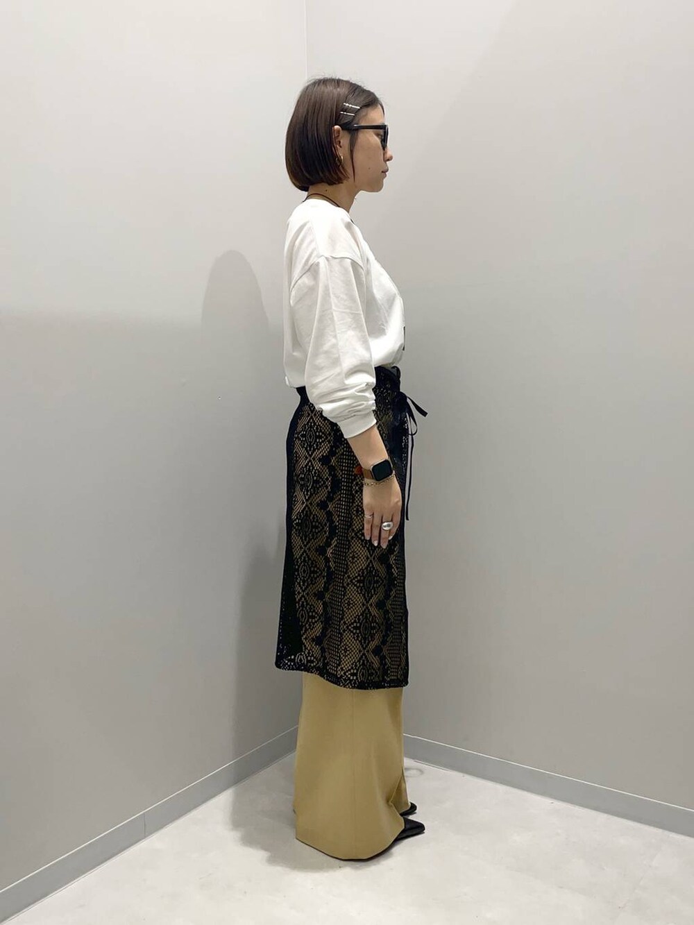 ベージュ系のその他パンツ、ホワイト系のTシャツ/カットソー、ブラック系のその他小物を着用したレディースの春コーディネートの2枚目の写真