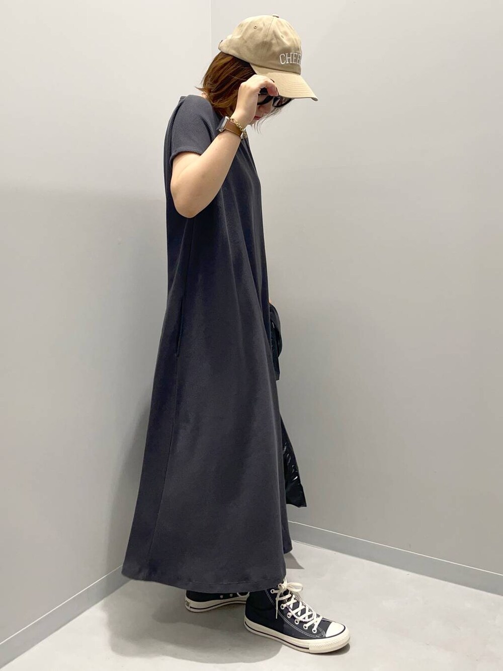 ブラック系のトートバッグ、グレー系のワンピース、ブラウン系のキャップを着用したレディースの夏コーディネートの2枚目の写真