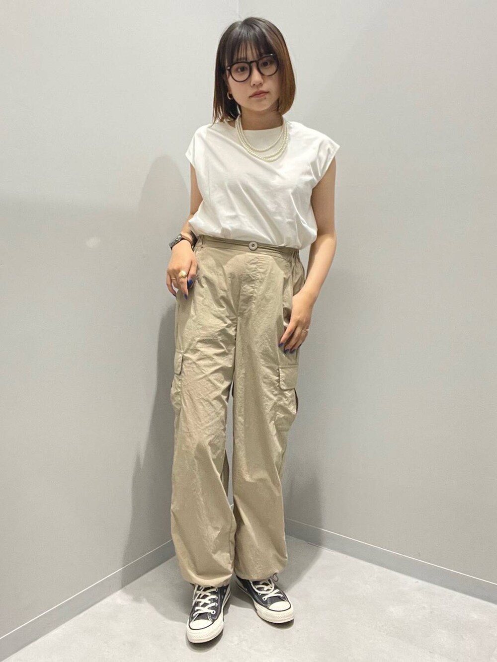 ベージュ系のカーゴパンツ、ホワイト系のタンクトップを着用したレディースの夏コーディネートの2枚目の写真
