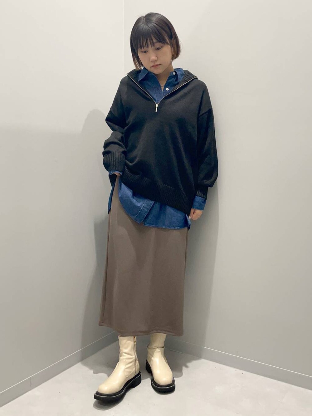 ブラック系のニット/セーター、ブルー系のシャツ/ブラウス、ブラウン系のスカートを着用したレディースの秋コーディネートの2枚目の写真