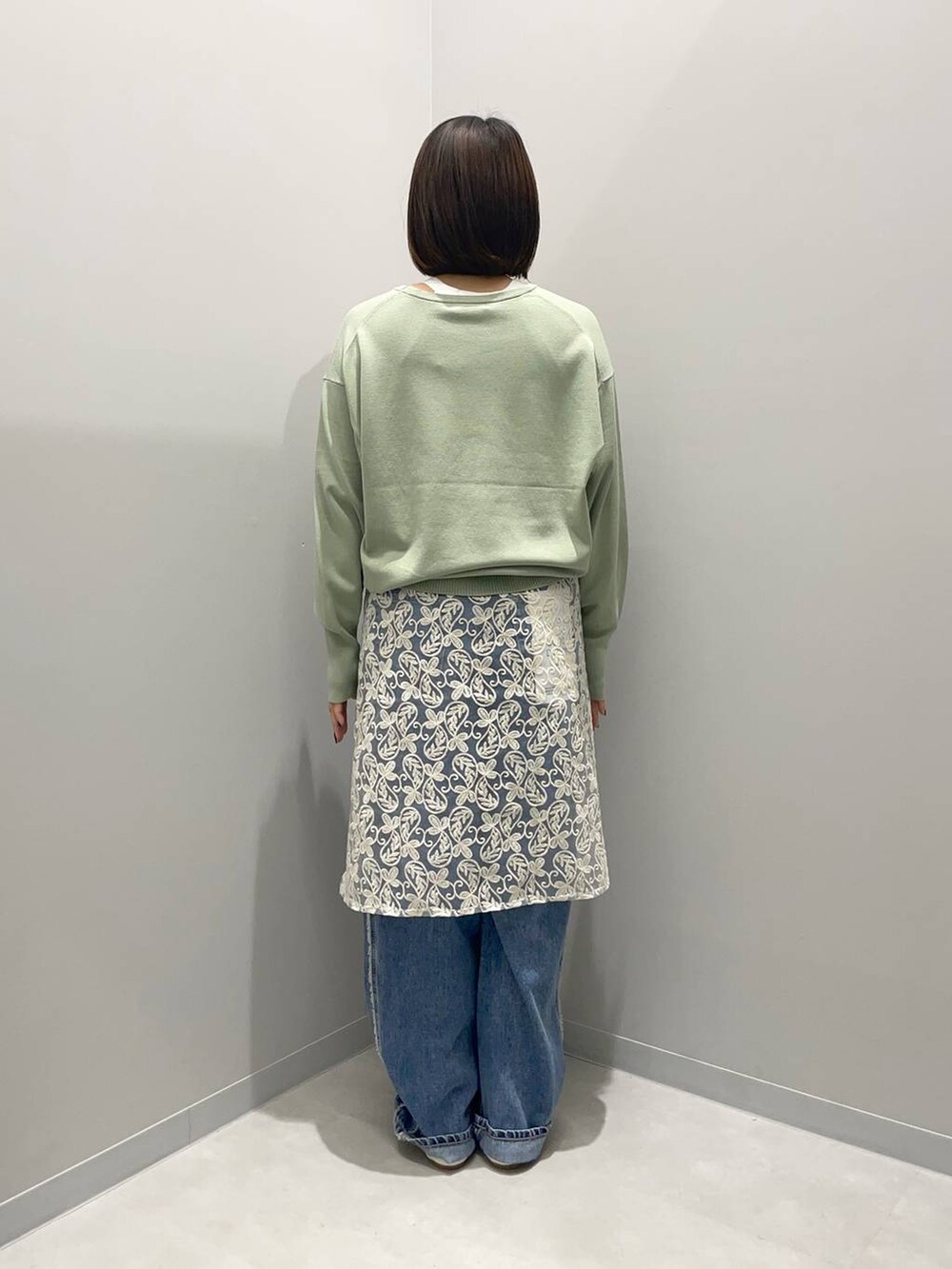 ホワイト系のデニムパンツ、グリーン系のニット/セーター、ホワイト系のその他小物を着用したレディースの春コーディネートの3枚目の写真