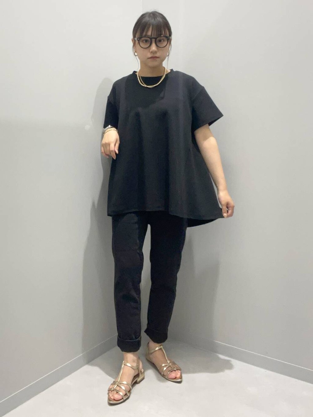 ブラック系のTシャツ/カットソー、ブラック系のデニムパンツ、イエロー系のネックレスを着用したレディースの夏コーディネートの2枚目の写真