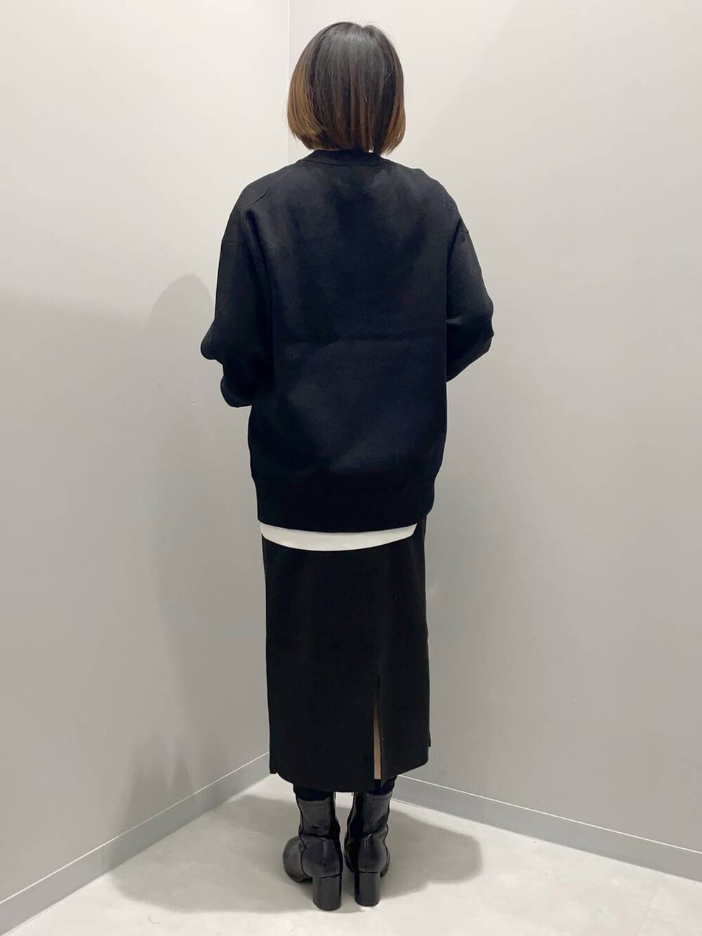 ブラック系のニット/セーター、ホワイト系のTシャツ/カットソー、ブラック系のスカートを着用したレディースの秋コーディネートの4枚目の写真