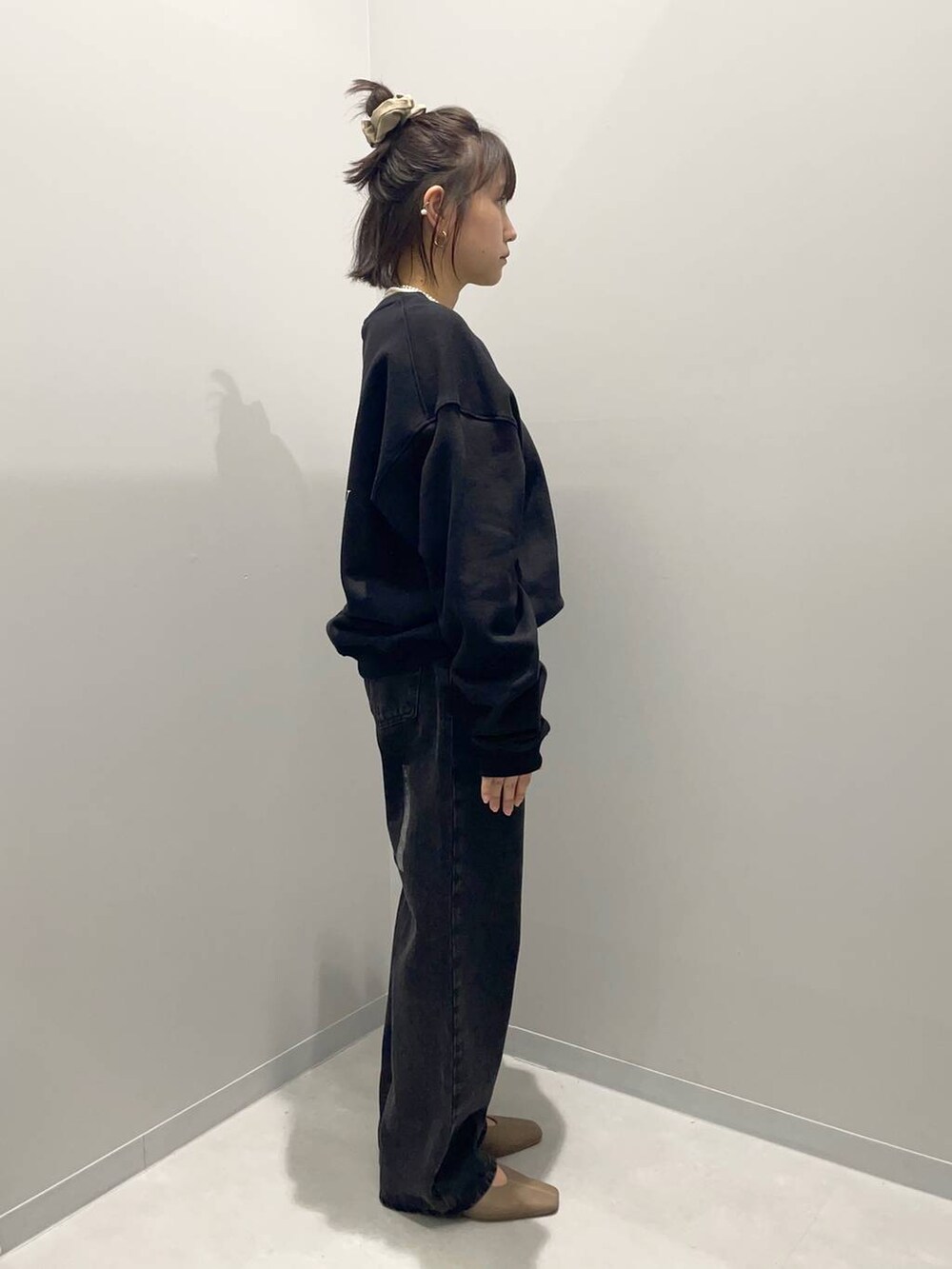 ブラック系のデニムパンツ、ブラウン系のハンドバッグ、ブラック系のスウェットを着用したレディースの秋コーディネートの3枚目の写真