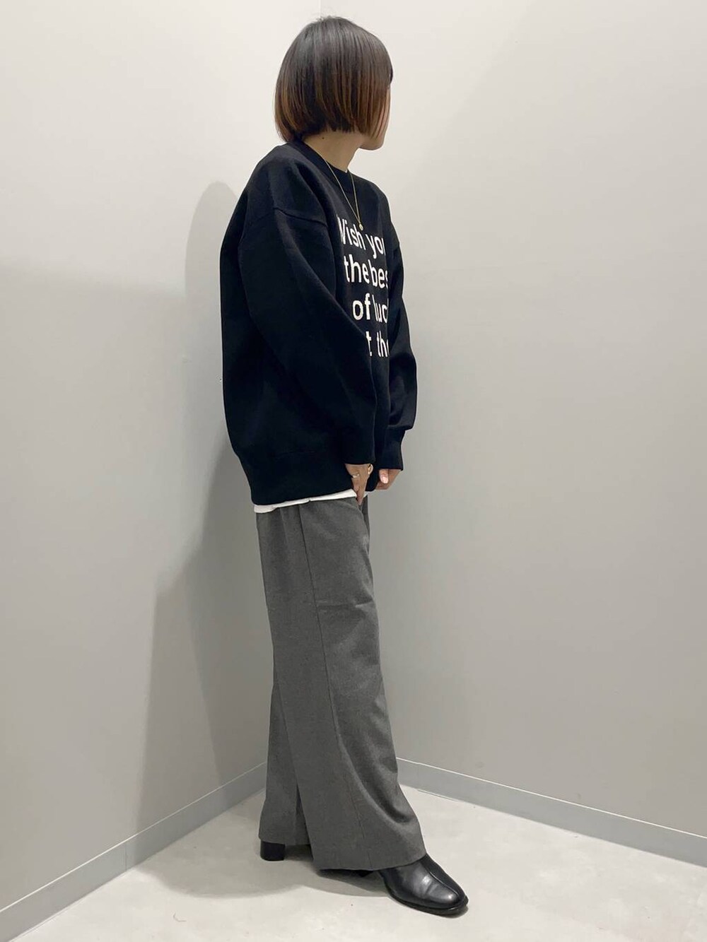 グレー系のその他パンツ、ホワイト系のTシャツ/カットソー、ブラック系のニット/セーターを着用したレディースの秋コーディネートの2枚目の写真