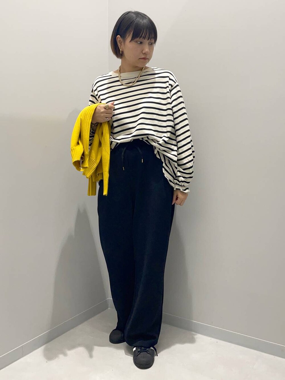 イエロー系のニット/セーター、グレー系のTシャツ/カットソー、ブラック系のその他パンツを着用したレディースの秋コーディネートの4枚目の写真