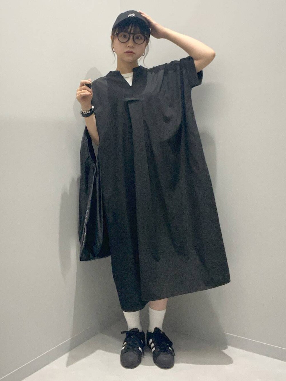 ブラック系のトートバッグ、ブラック系のシャツワンピース、ブラック系のキャップを着用したレディースの夏コーディネートの2枚目の写真