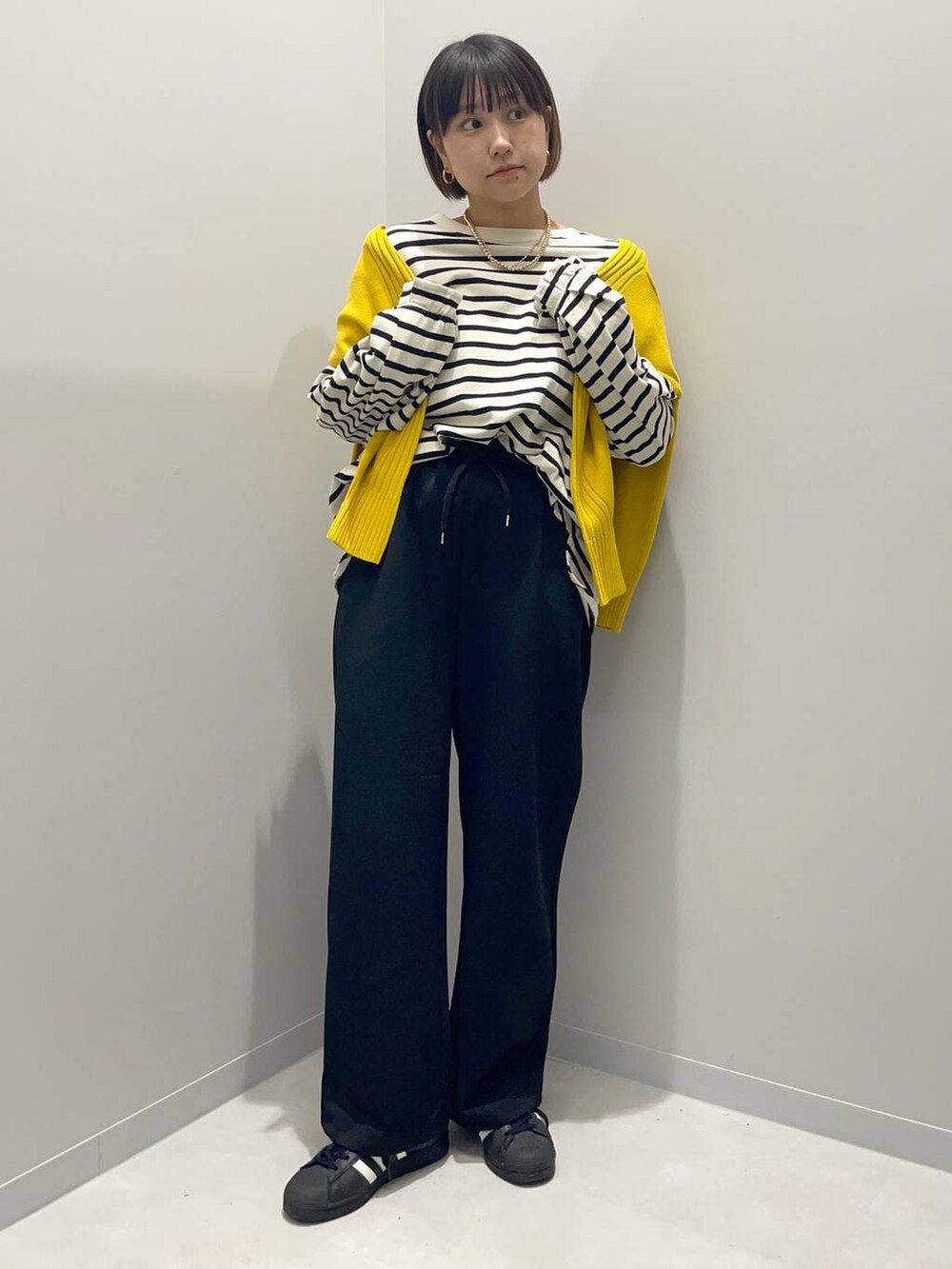 イエロー系のニット/セーター、グレー系のTシャツ/カットソー、ブラック系のその他パンツを着用したレディースの秋コーディネートの2枚目の写真