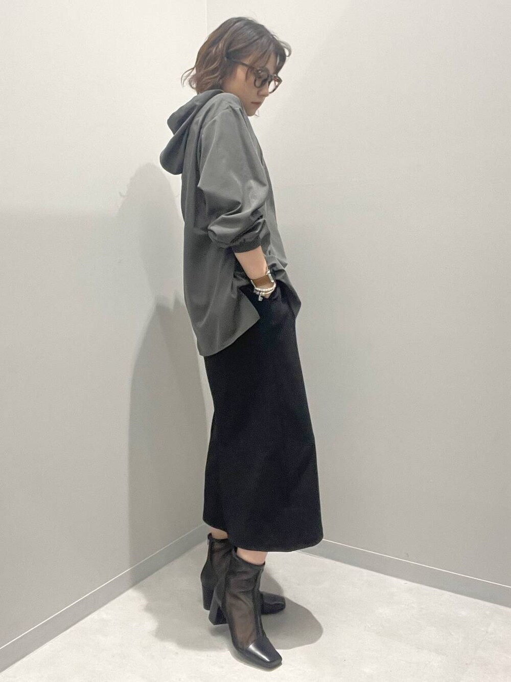 ブラック系のスカート、グレー系のブルゾン、ホワイト系のネックレスを着用したレディースの春コーディネートの2枚目の写真