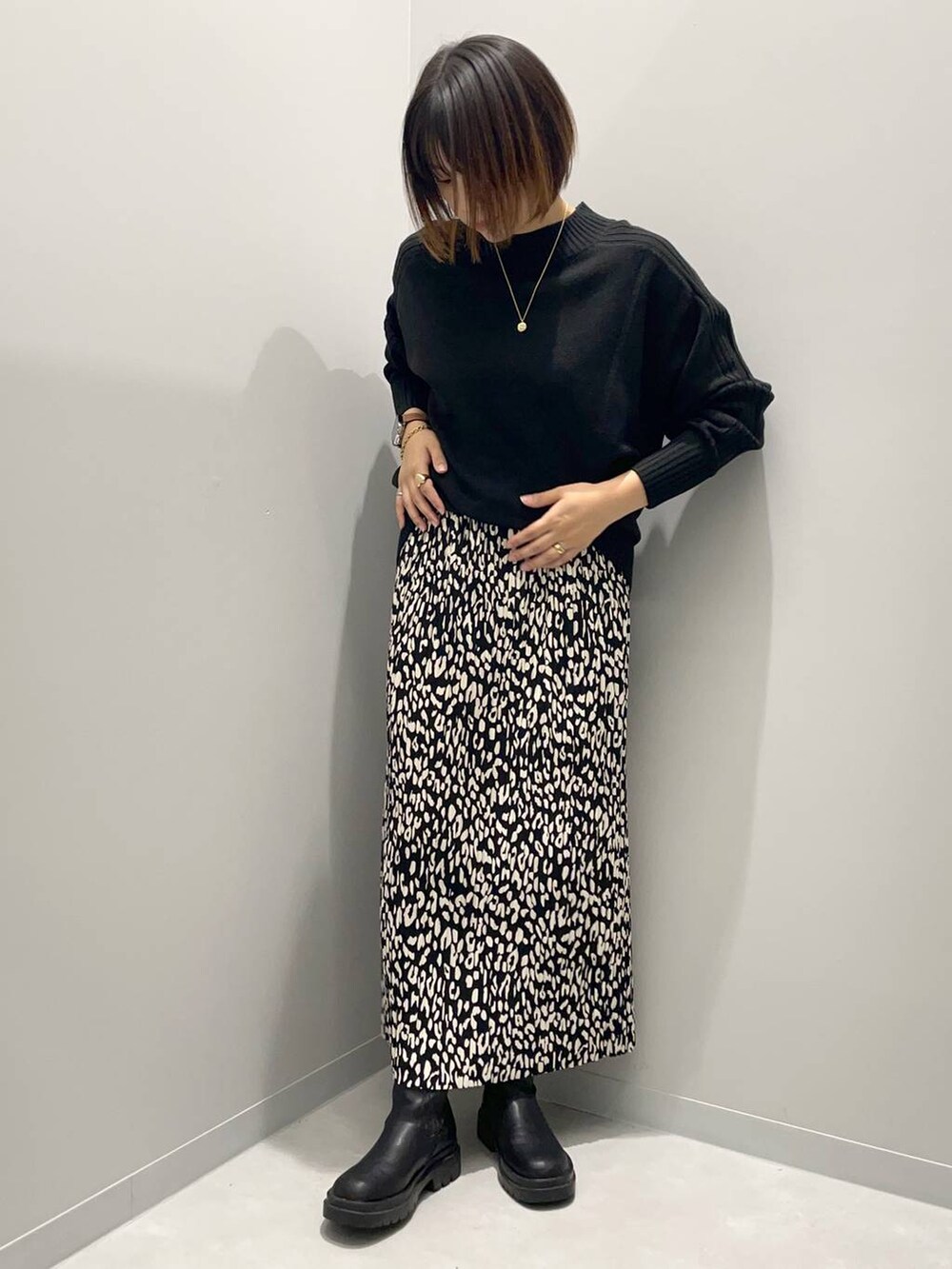 ブラック系のニット/セーター、グレー系のスカートを着用したレディースの秋コーディネートの2枚目の写真