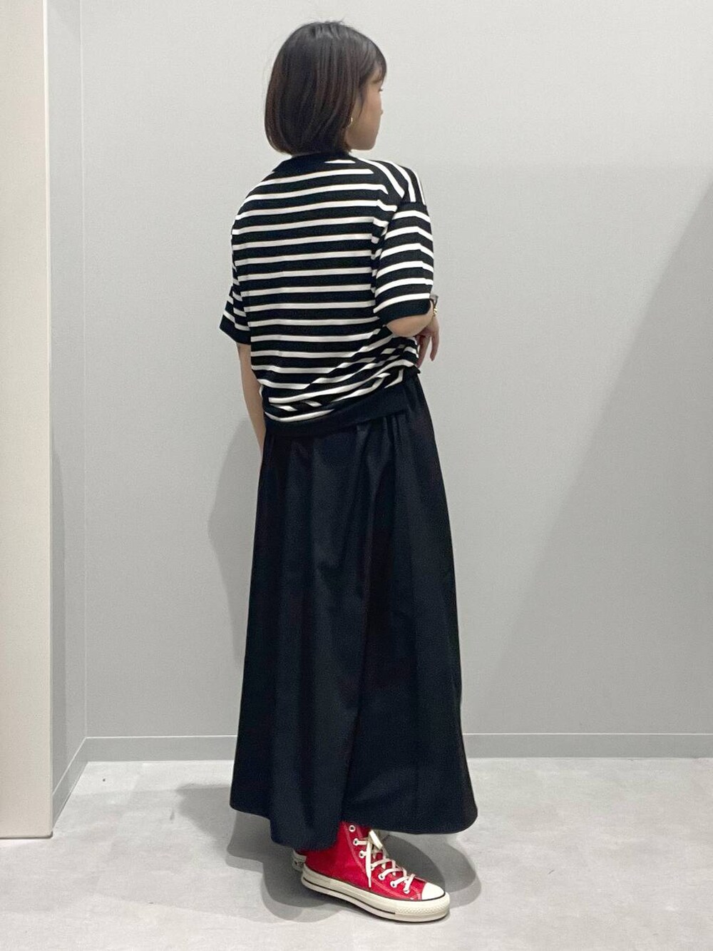 ブラック系のスカート、グレー系のニット/セーター、ホワイト系のネックレスを着用したレディースの春コーディネートの3枚目の写真